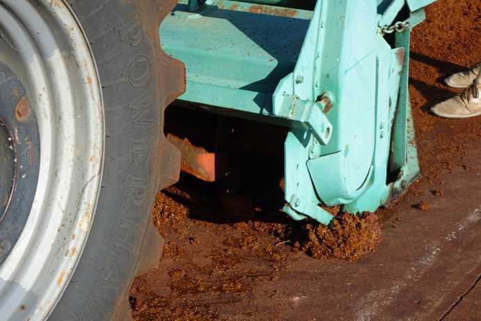 Blick von vorne in das Traktor-Anbaugerät, das den fermentierten Rooibos belüftet und im selben Arbeitsgang in eine angehäufelte Reihe legt. Der Rooibos wird dreimal abwechselnd gepresst und belüftet, bevor die Reihe in die Mitte des Tea Courts geschoben wird.