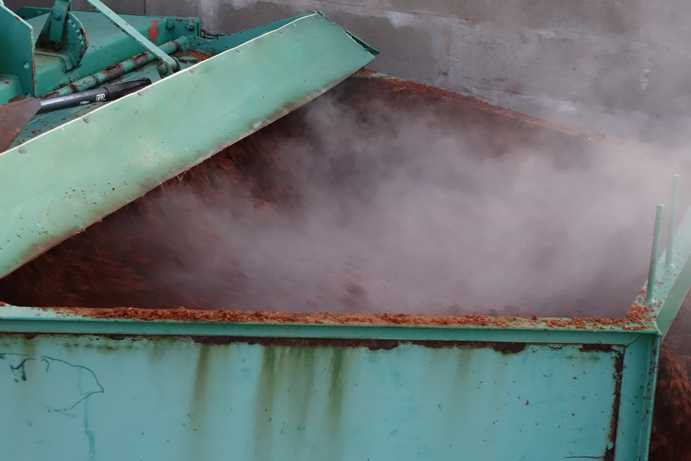 Blick von oben in das Traktor-Anbaugerät, das den fermentierten Rooibos belüftet und gleichzeitig in einer angehäufelten Reihe ablegt. Das nach hinten verjüngte Gehäuse des rotierenden Messers sorgt dafür, dass der Rooibos in einer gleichmäßig angehäufelten Reihe abgelegt wird.