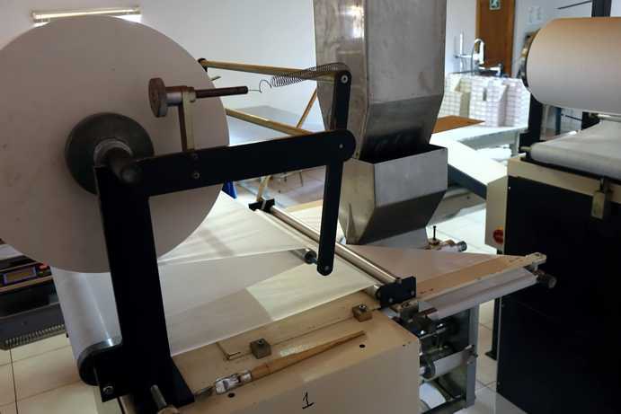 The image shows a tea bag manufacturing machine on the Klipfontein Farm. Clearly visible is how the filter material is unwound from a large roll and fed into the machine. Inside, the Rooibos is enclosed between two layers of filter material before the edges are sealed.