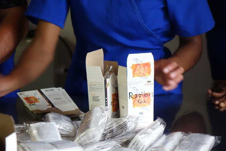 Workers on the Klipfontein Farm pack airtight-sealed Rooibos tea bags into branded packaging with the name Kings Products.