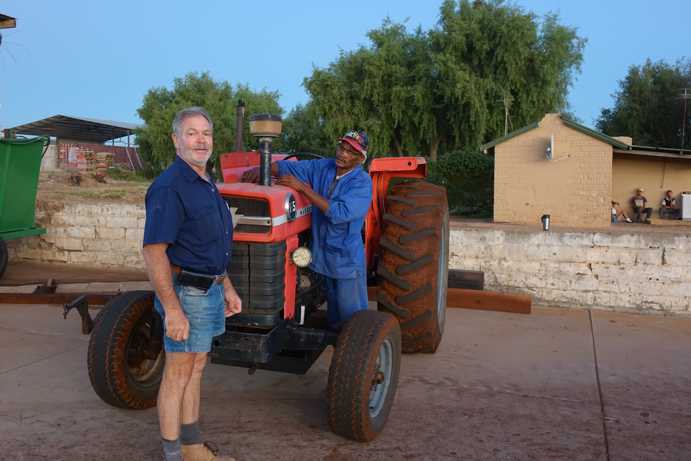 Paul Smit se tient devant un tracteur, où le conducteur utilise des équipements spécialisés pour les étapes suivantes du processus. Lors de la première étape, le Rooibos fermenté est compacté avec les pneus du tracteur afin de répartir uniformément le liquide dans la masse de Rooibos.