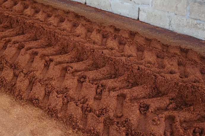 Empreintes des pneus du tracteur dans la masse de Rooibos fermenté. En passant dessus, le tracteur compacte la masse, permettant ainsi au liquide de se répartir uniformément dans les morceaux de Rooibos.